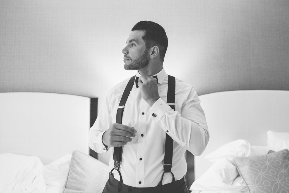 groom tying up his bow tie
