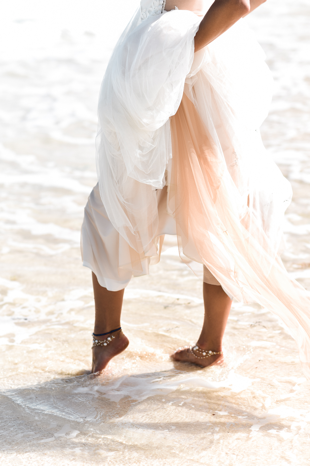 Bride standing in Bermuda water with ankle bracelets 