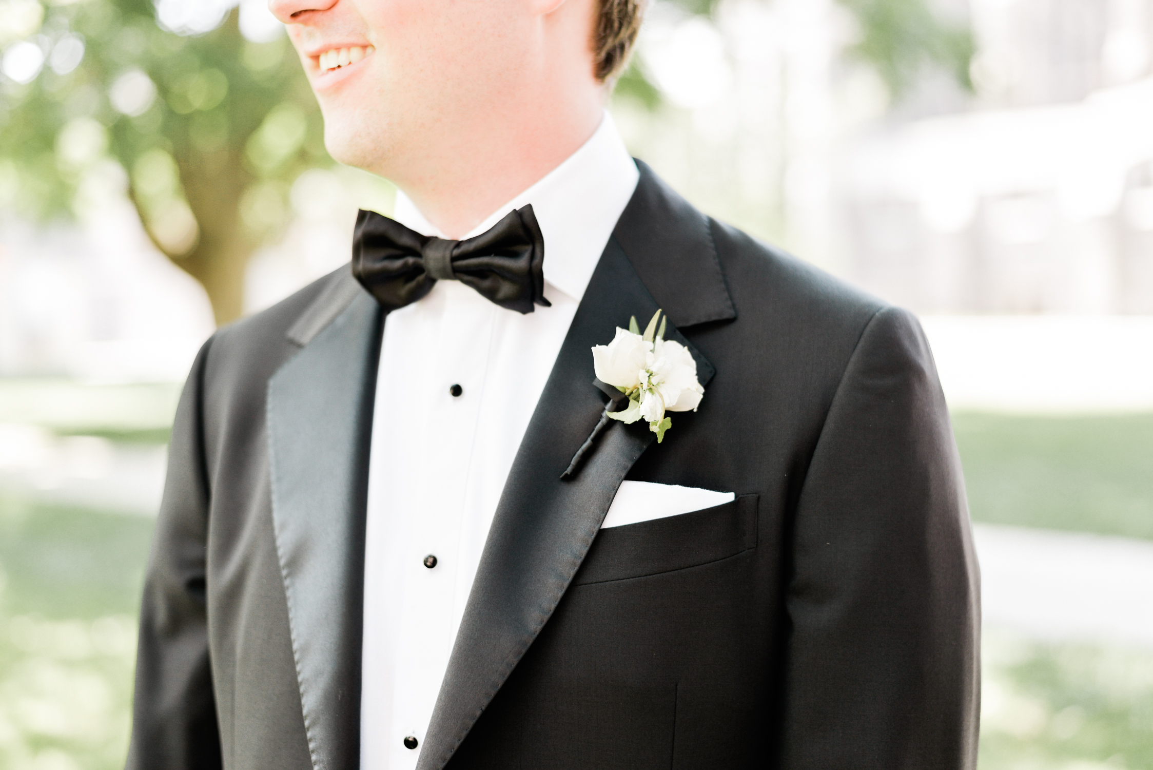 groom in blck tux with black bow tie and white boutonniere