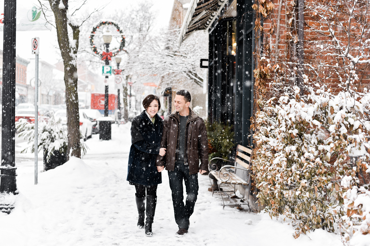 Couple walking through Dundas Ontario during a winter snowfall for their engagement session