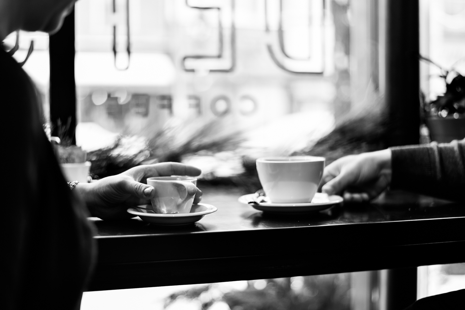Black and white photo of coffee mugs and hands