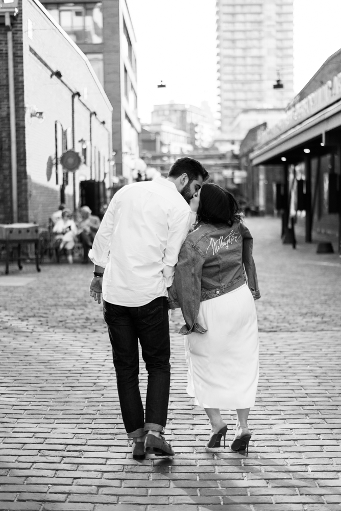 Black and white image of couple with a vintage jean jacket for their engagement shoot in the distillery district