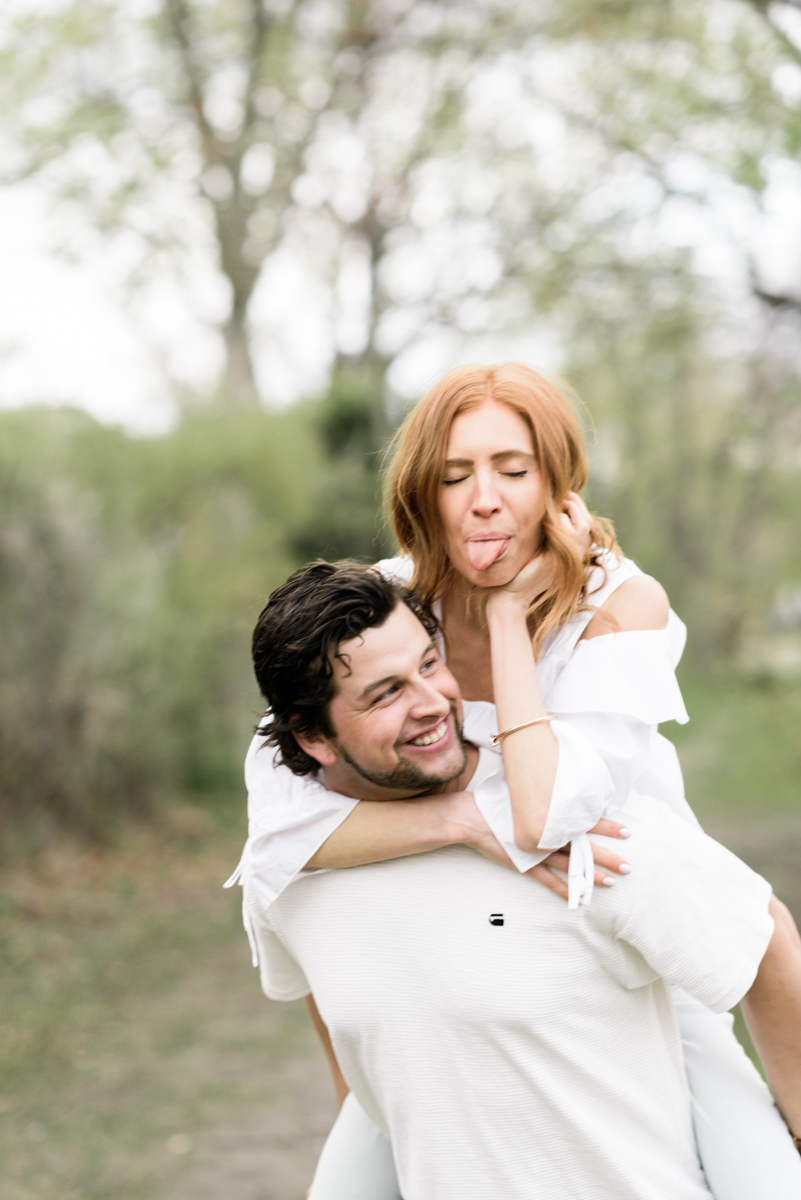 Engagement photo of girl on guy's back sticking her tongue