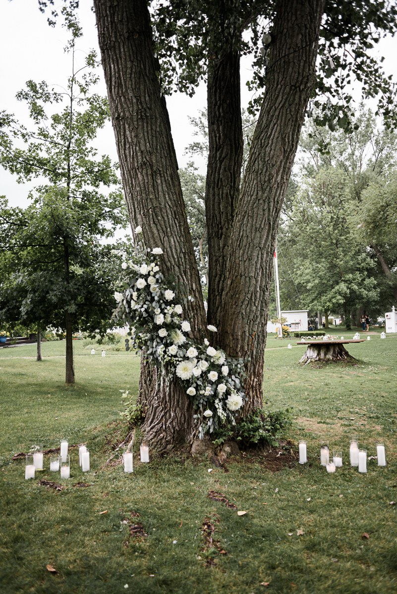 The most gorgeous flowers wrapping around a tree, with candles on the ground, for this wedding ceremony