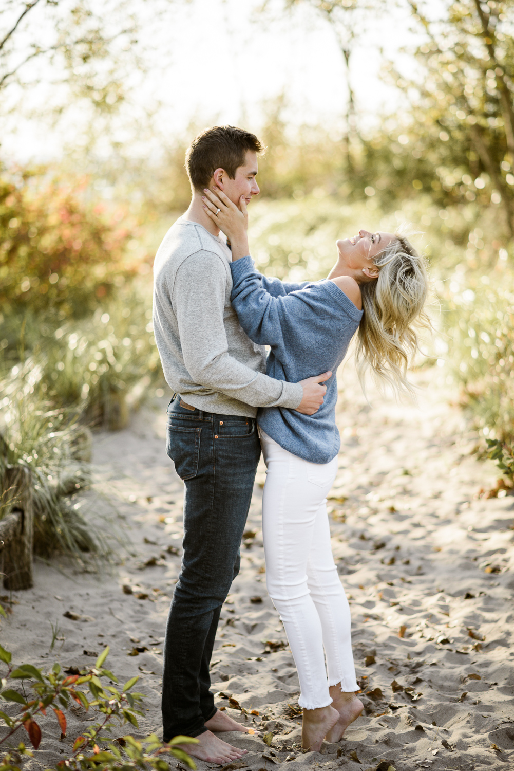 Blonde in blue sweater and man in grey sweater on the beach